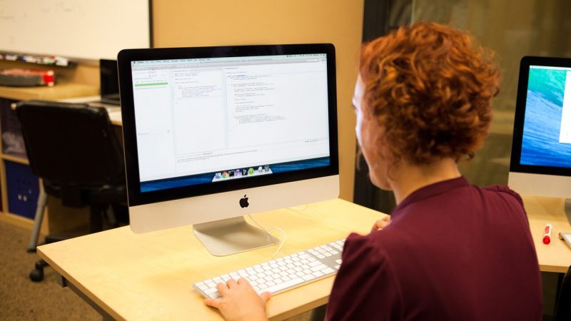 Programmer writing code on a desktop computer