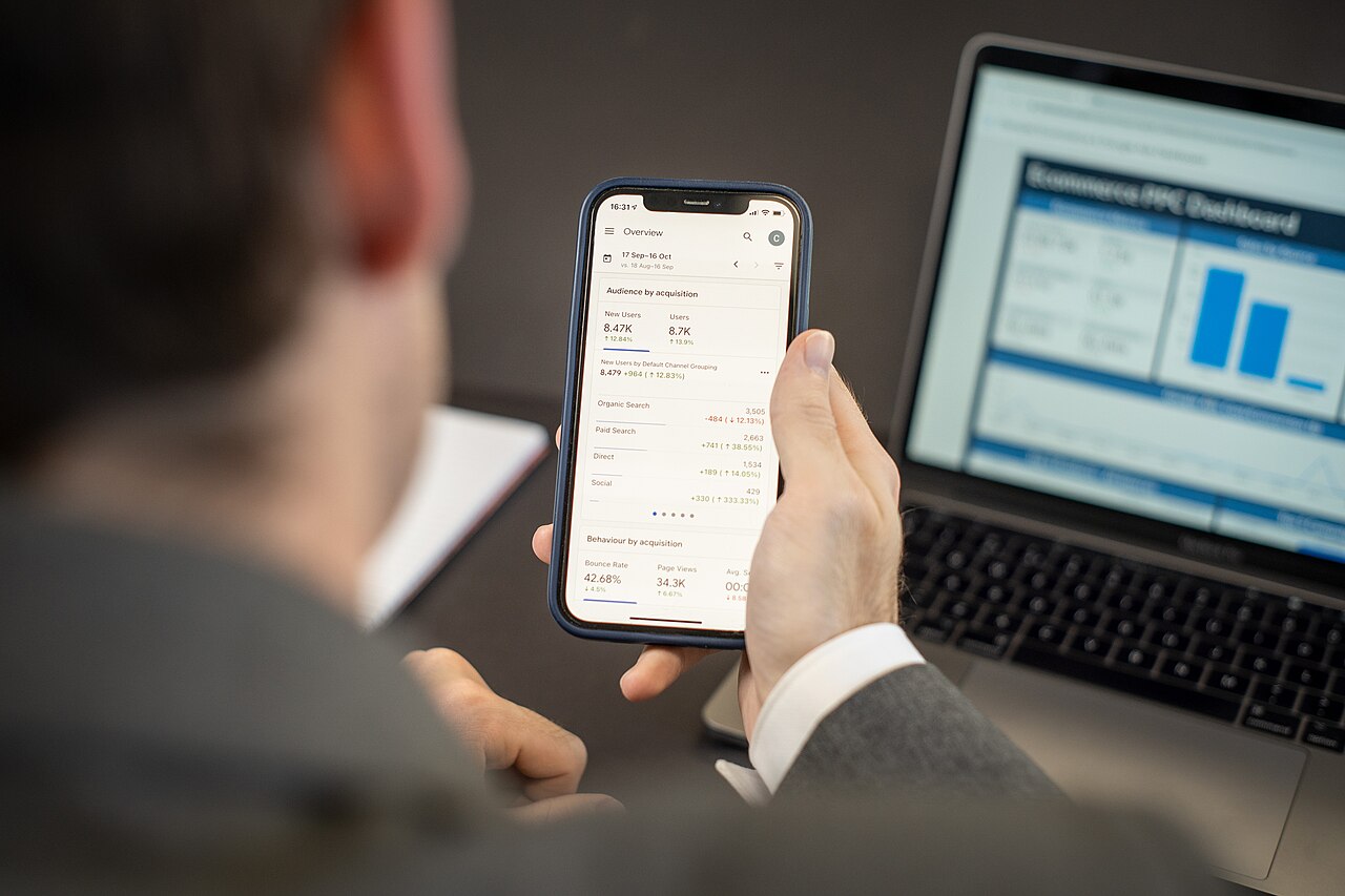 Person using a mobile app on a smartphone next to a laptop